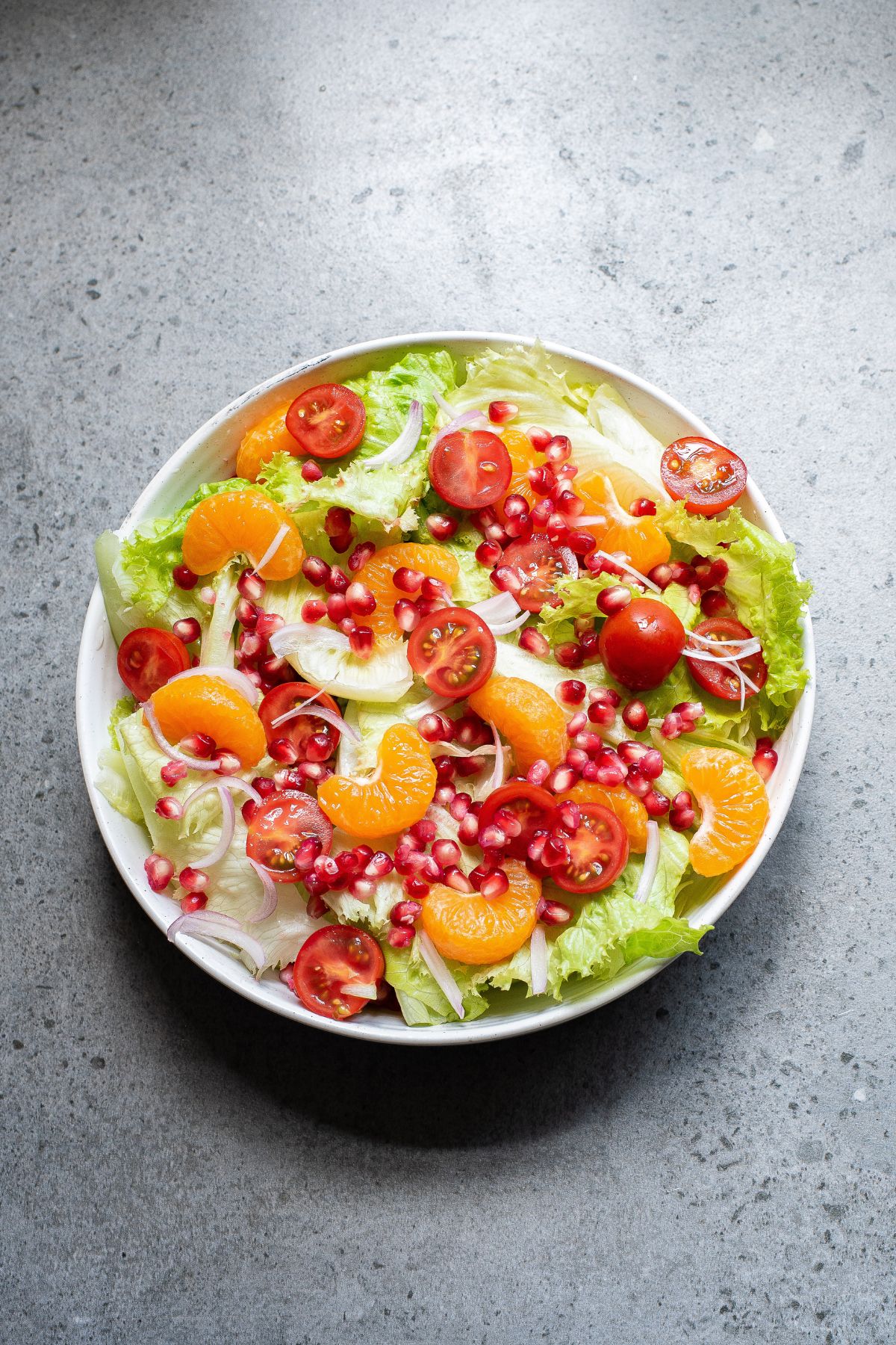 Leafy greens with vegetables and fruits in a bowl.