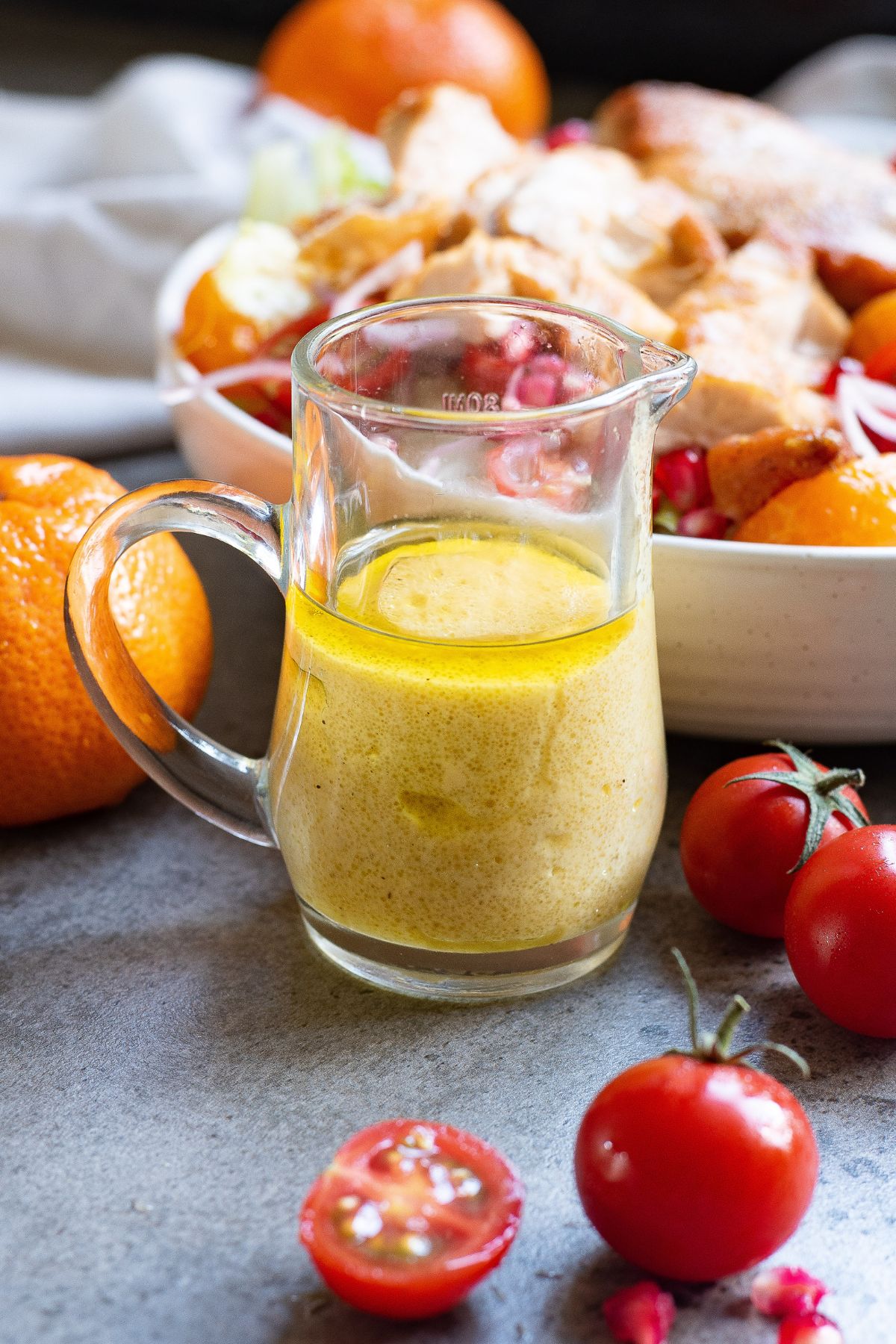 Salad dressing mixed in a clear glass container on a gray marble table. 