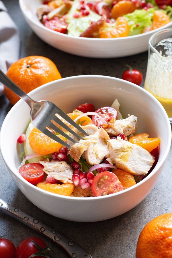 Small serving of salad in a white bowl being served with a fork 