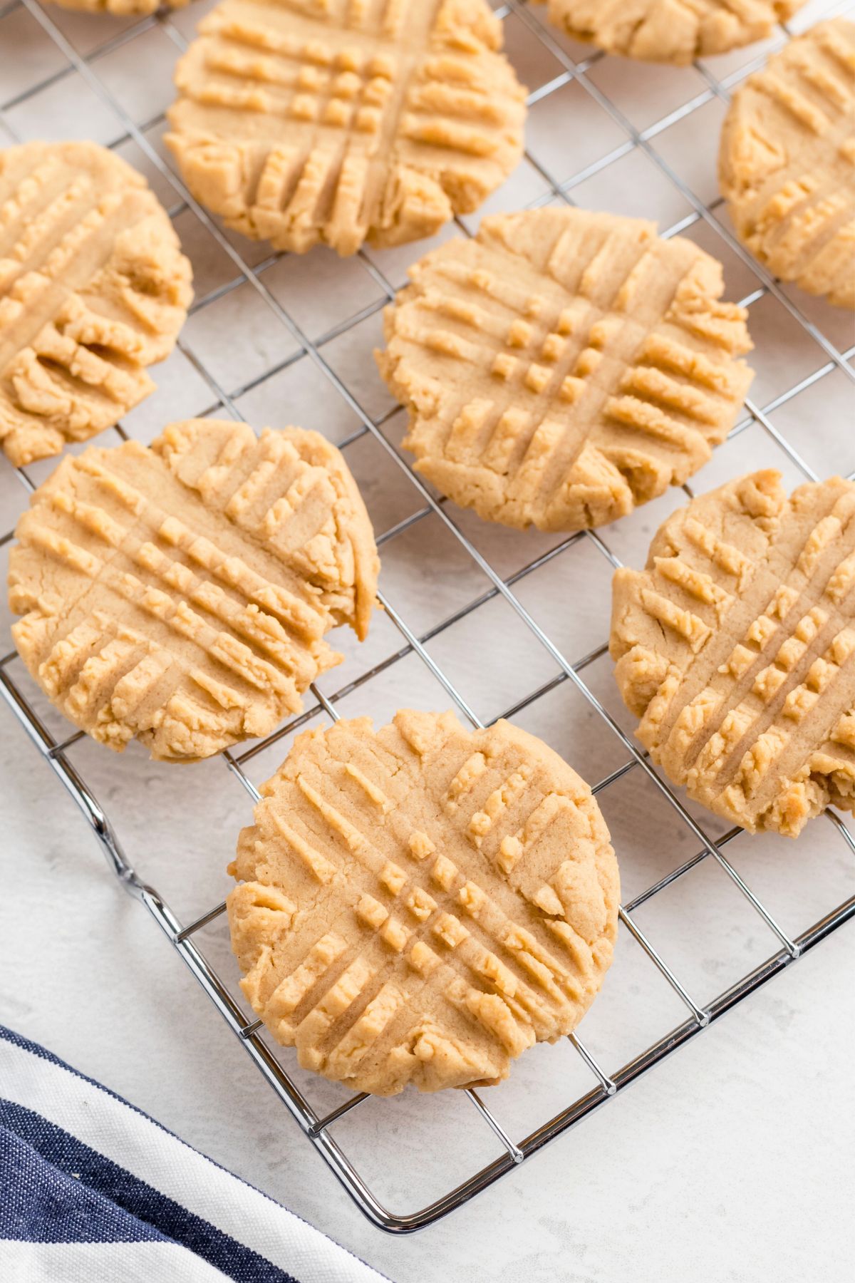 Golden brown peanut butter cookies cooling on a metal rack.