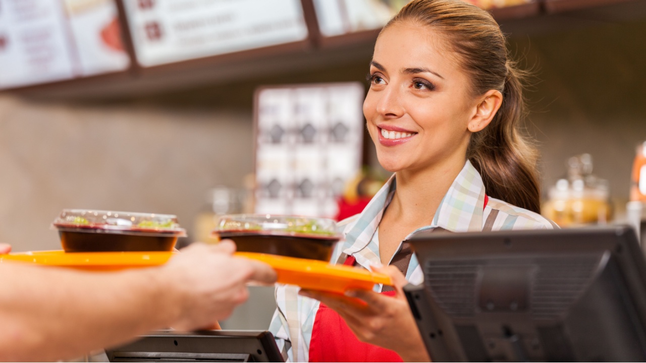 Restaurant worker serving two fast food meals with smile