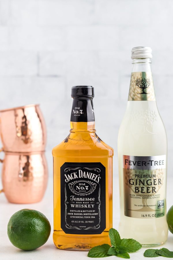 Ingredients to make Tennessee Mule on a marble table with a lime and mint leaves