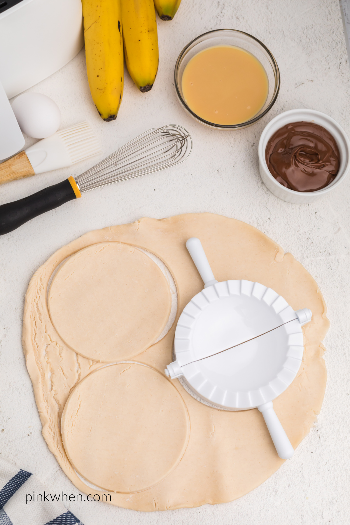 Pie crusts being cut from a sheet of pie dough.