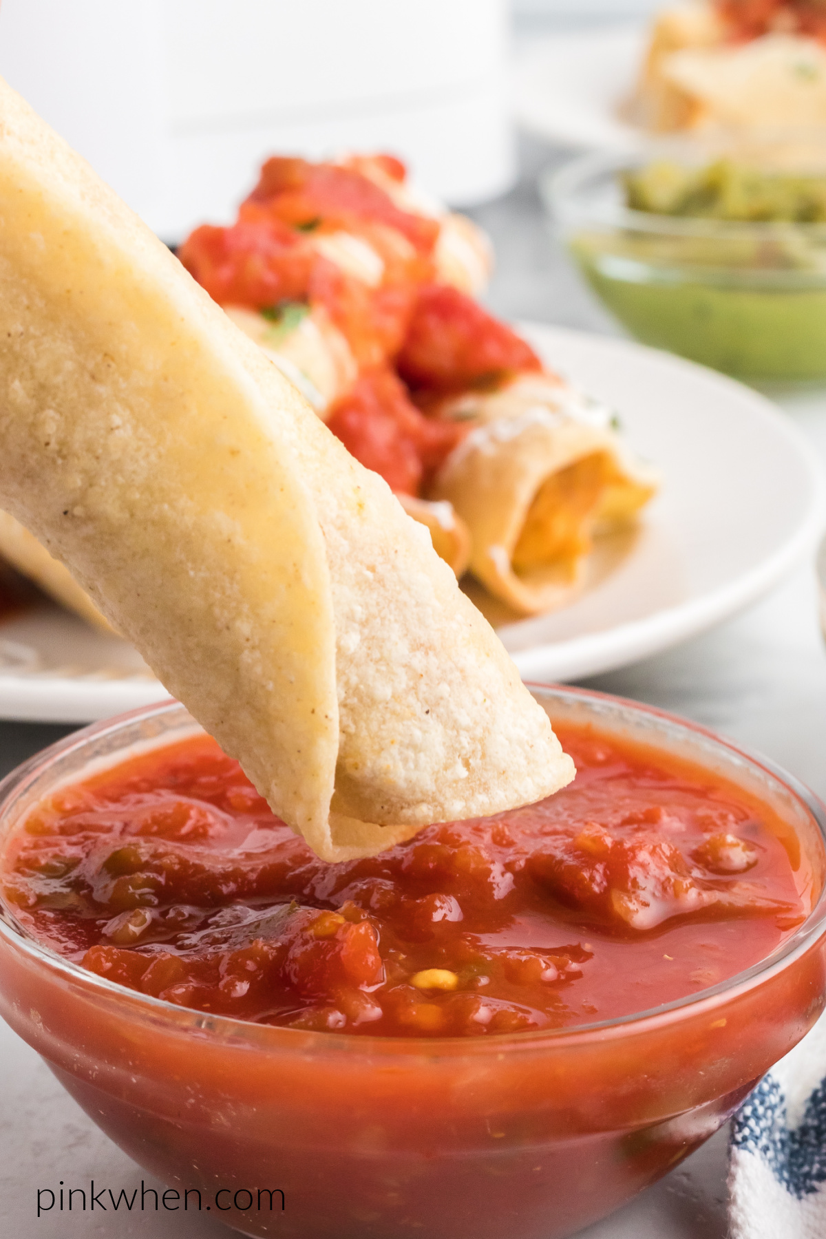 Air fryer chicken taquito being dipped in salsa. 