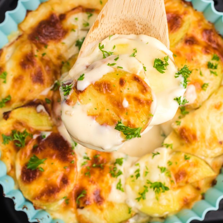 Air fryer scalloped potatoes being scooped from a silicone baking dish.