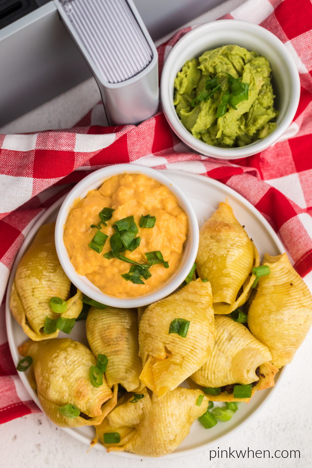 Taco stuffed shells made in the air fryer, on a plate with a serving of queso cheese for dipping.