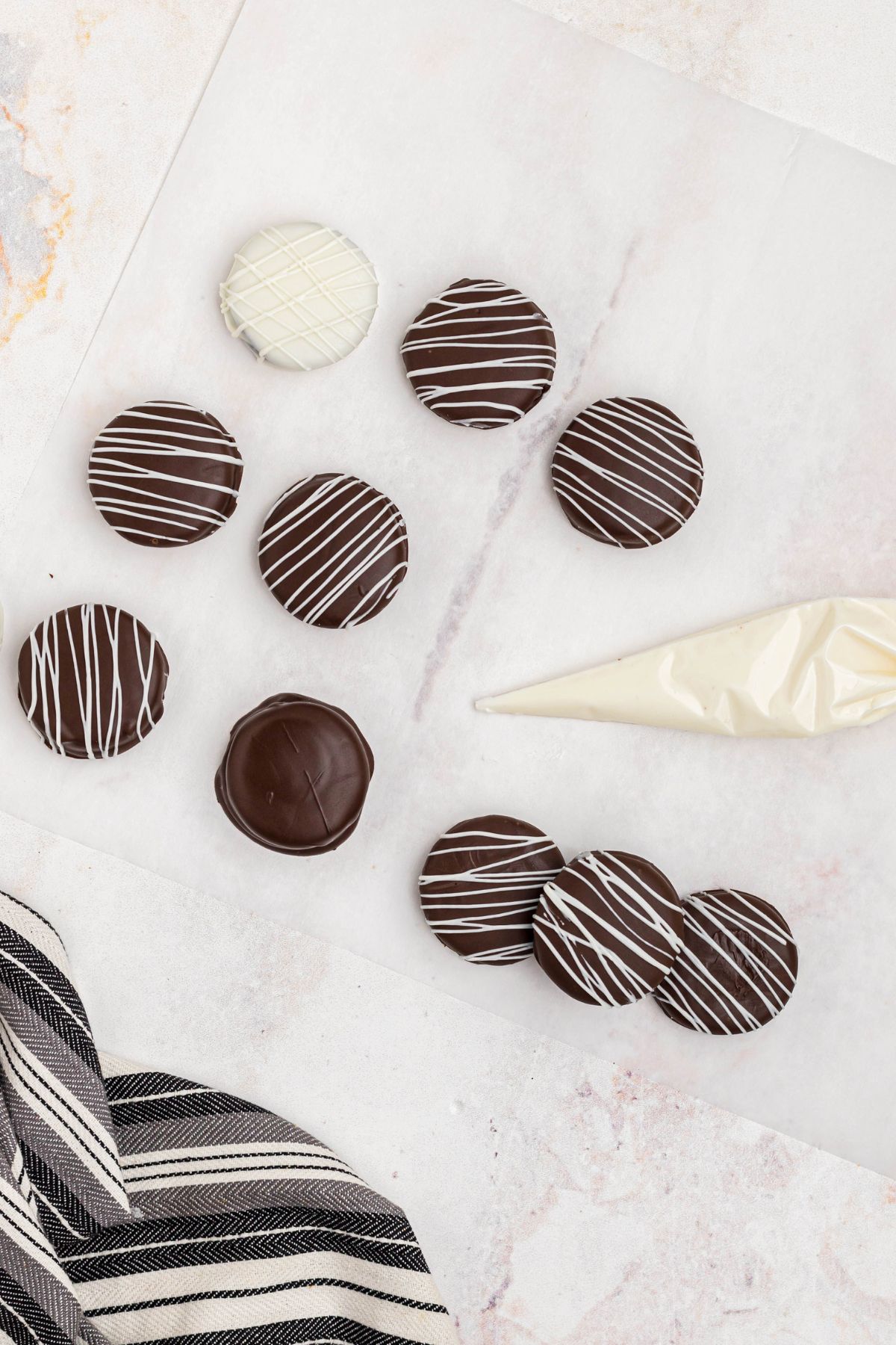 Chocolate covered Oreos drizzled with white chocolate in a piping bag.