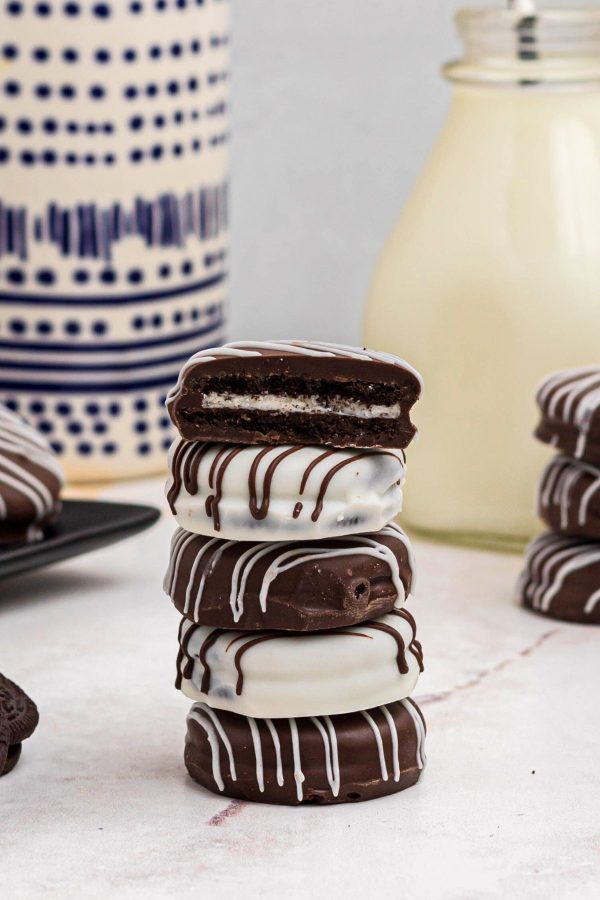 Oreo Cookies coated in chocolate and stacked in front of a glass of milk
