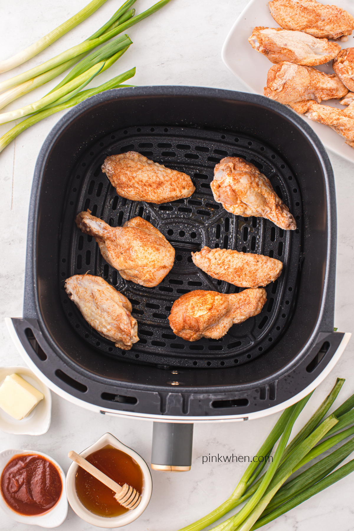 Wings cooking in the air fryer basket.