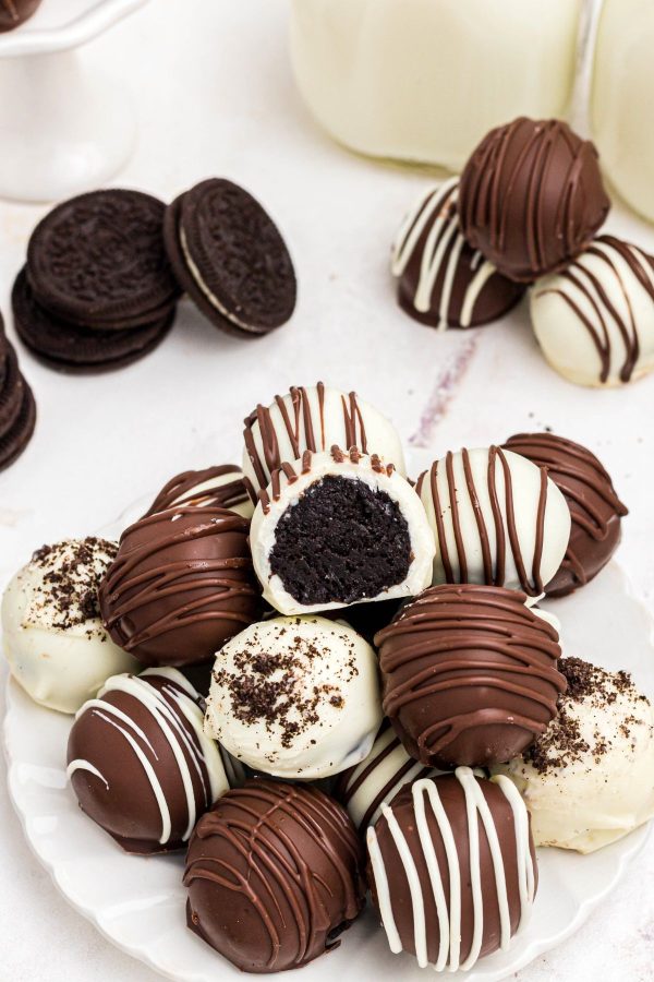 White chocolate and milk chocolate covered Oreo balls stacked on a white plate. 
