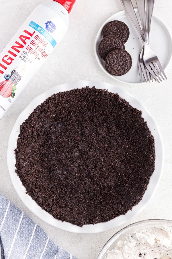 Oreos crushed and mixed with melted butter in a white pie plate.