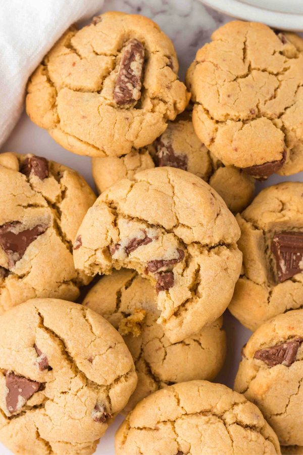 Golden baked peanut butter cookies with chocolate chunks baked in them with a bite taken on the top cookie