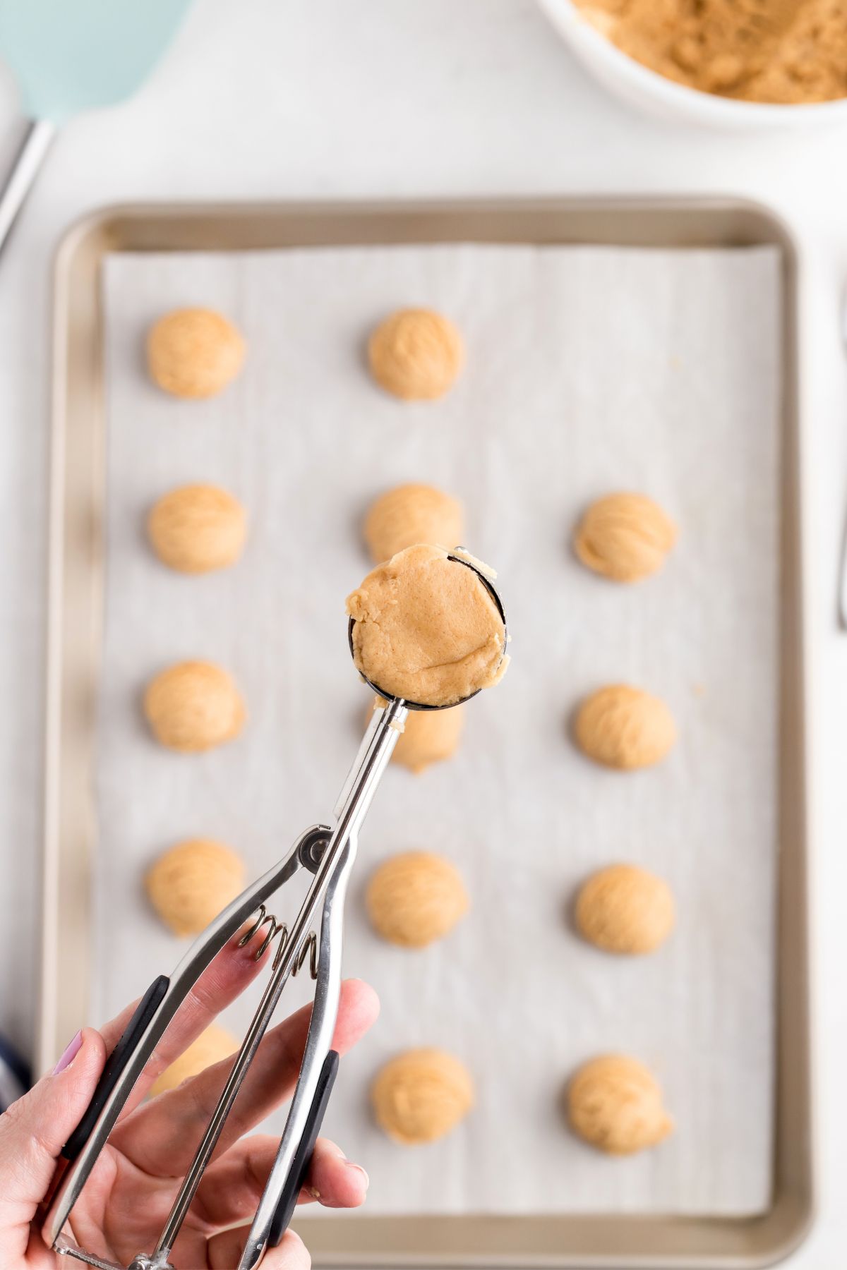 Uncooked cookie dough scooped into balls and placed on a baking sheet lined with parchment paper. 