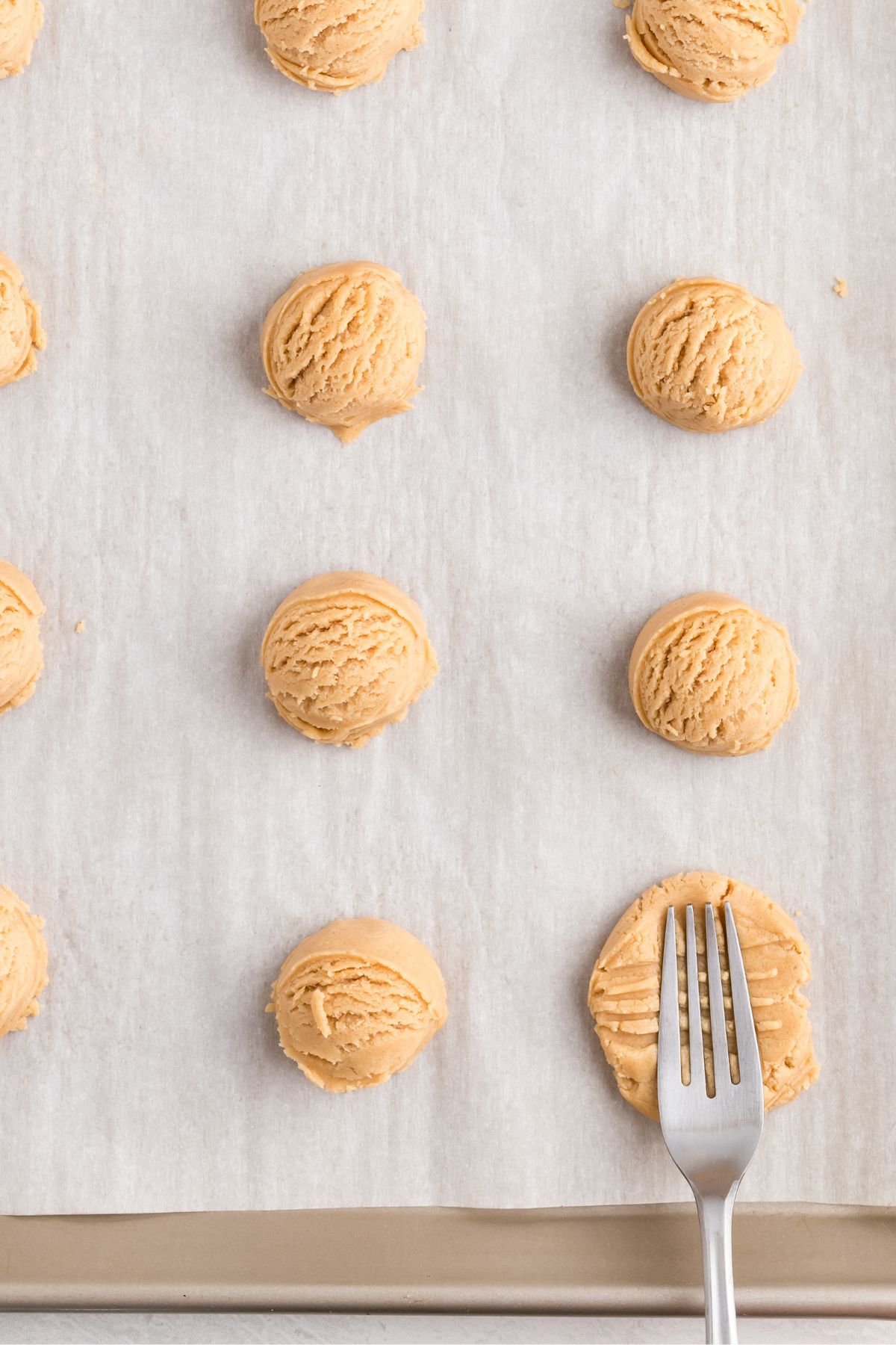 Peanut butter cookie dough balls having criss cross marks made on them with a a fork