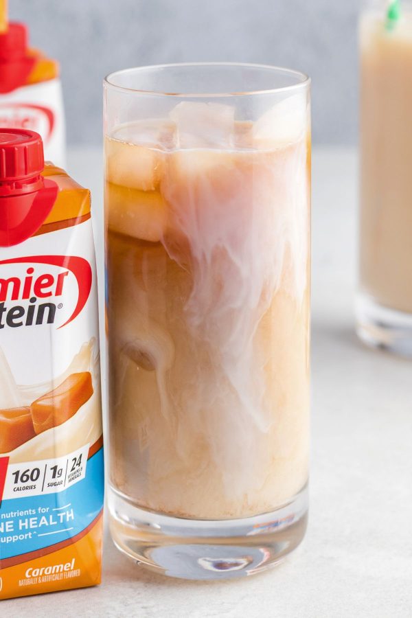 Clear tall glass of iced coffee on a white marble table