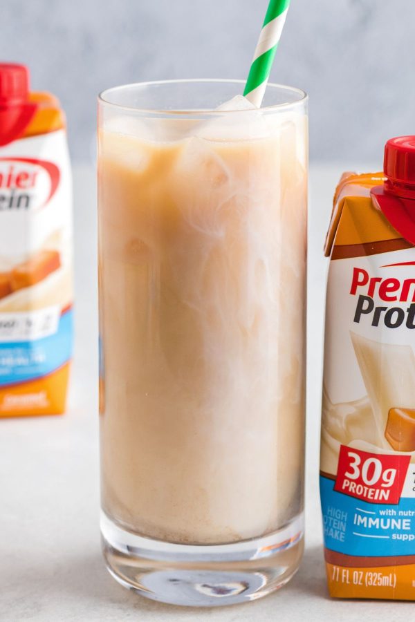 Creamy iced coffee in a tall clear glass with a green straw