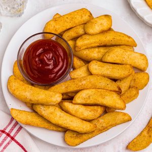 Golden seasoned Red Robin steak fries on a white plate with a small bowl of ketchup.
