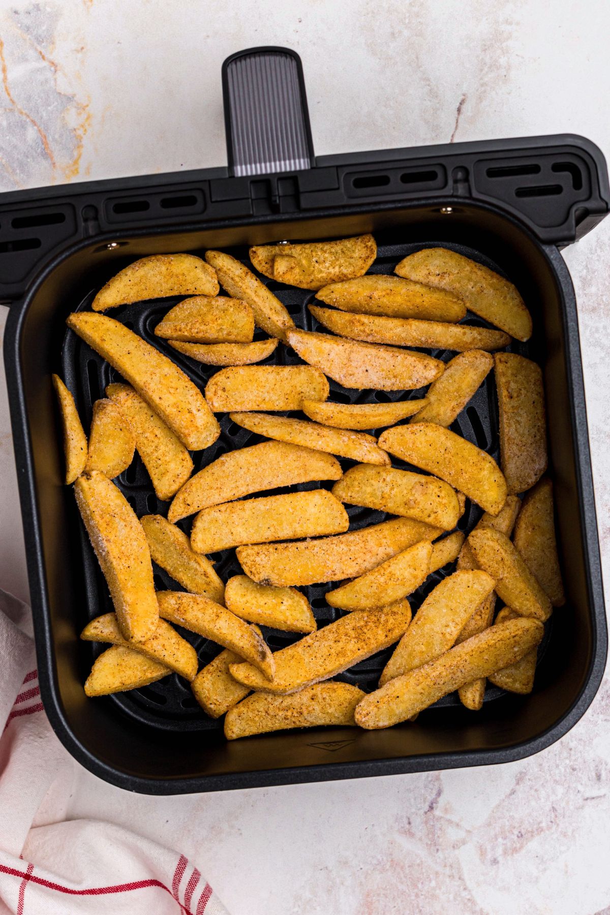  Frozen steak fries in the air fryer basket.