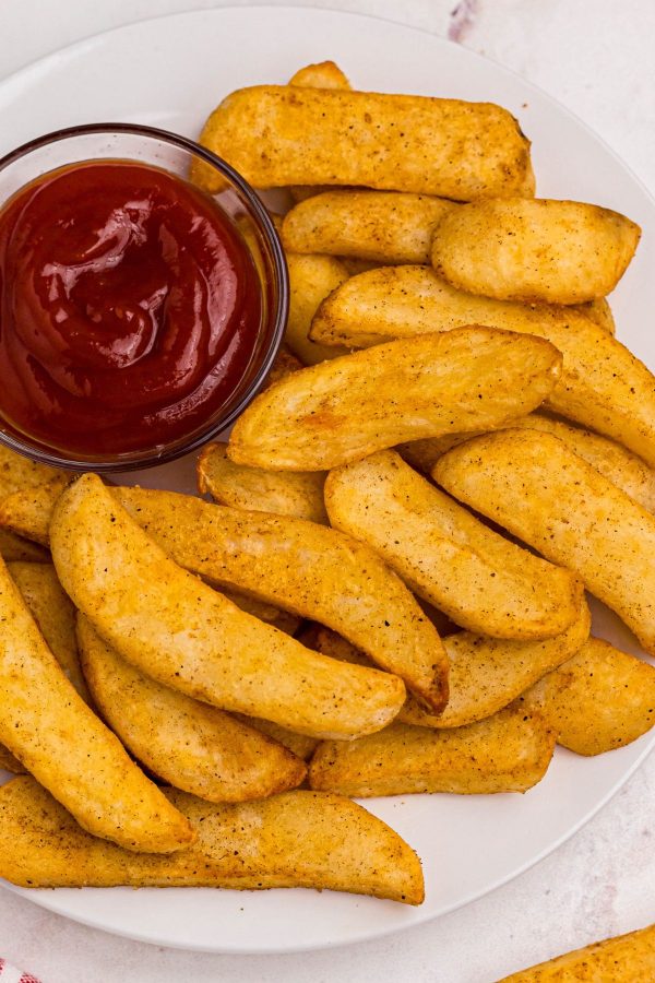 Golden seasoned Red Robin steak fries on a white plate with ketchup.