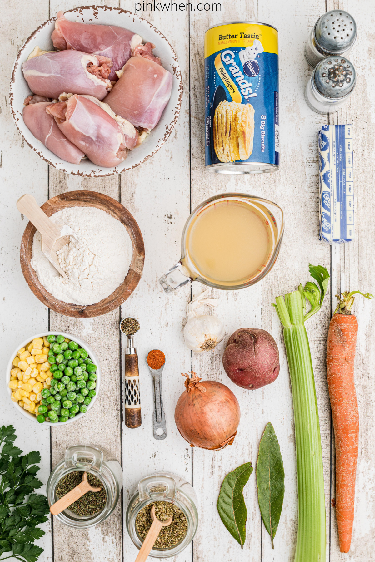 vegetables, chicken stock, chicken, biscuits, flour, and seasonings on a table for chicken pot pie.