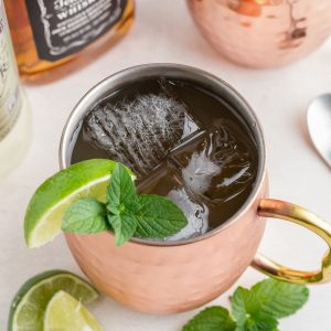 Copper mule mug filled with whiskey, ginger beer, and lime juice with a lime garnish.