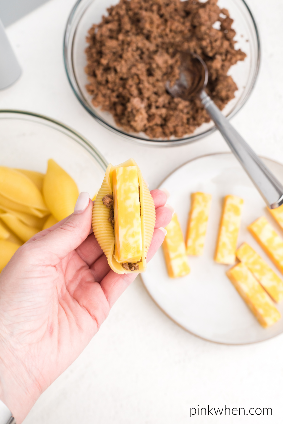 Cheese on top of taco meat in a jumbo shell.