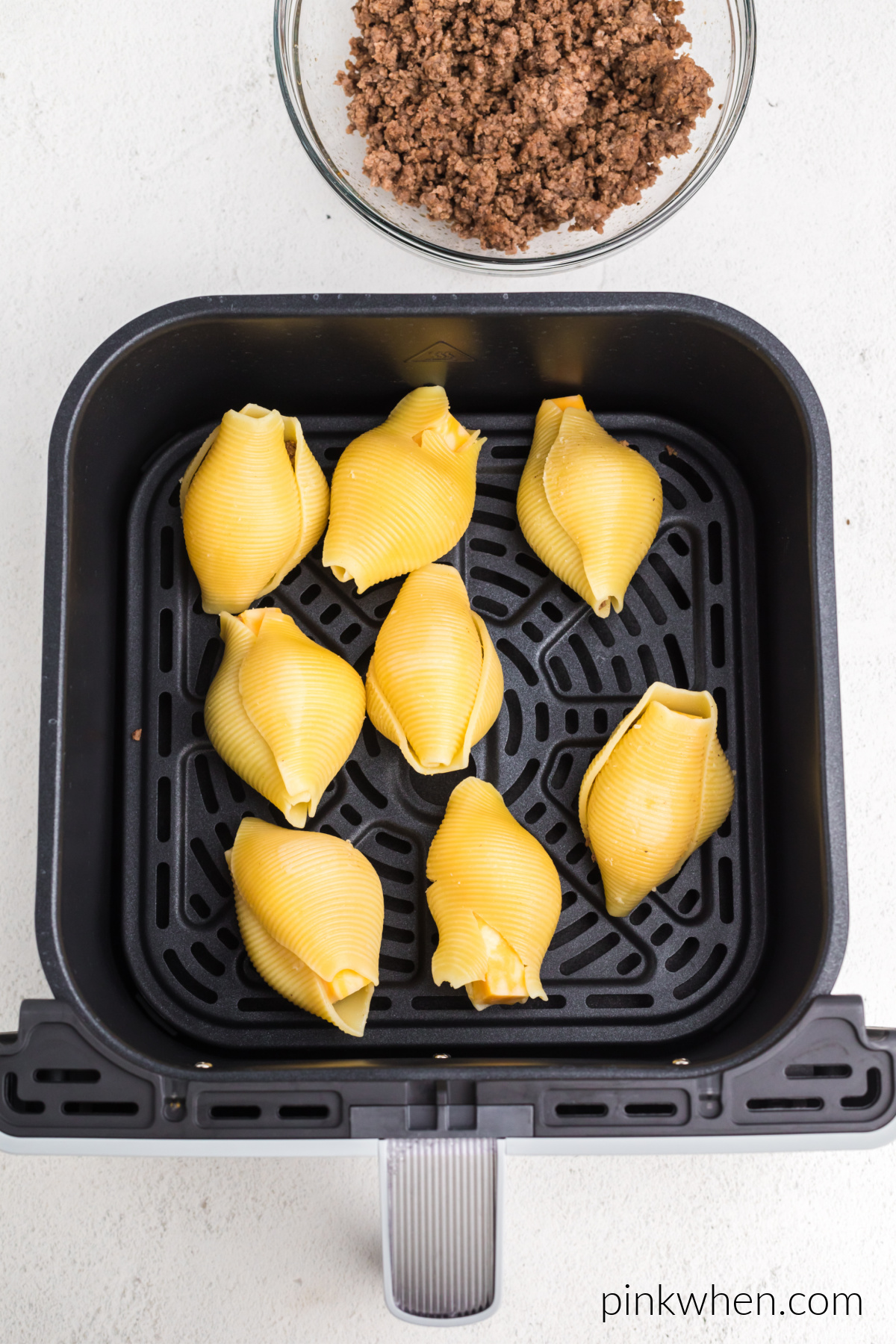 Taco stuffed shells in air fryer basket ready to cook.