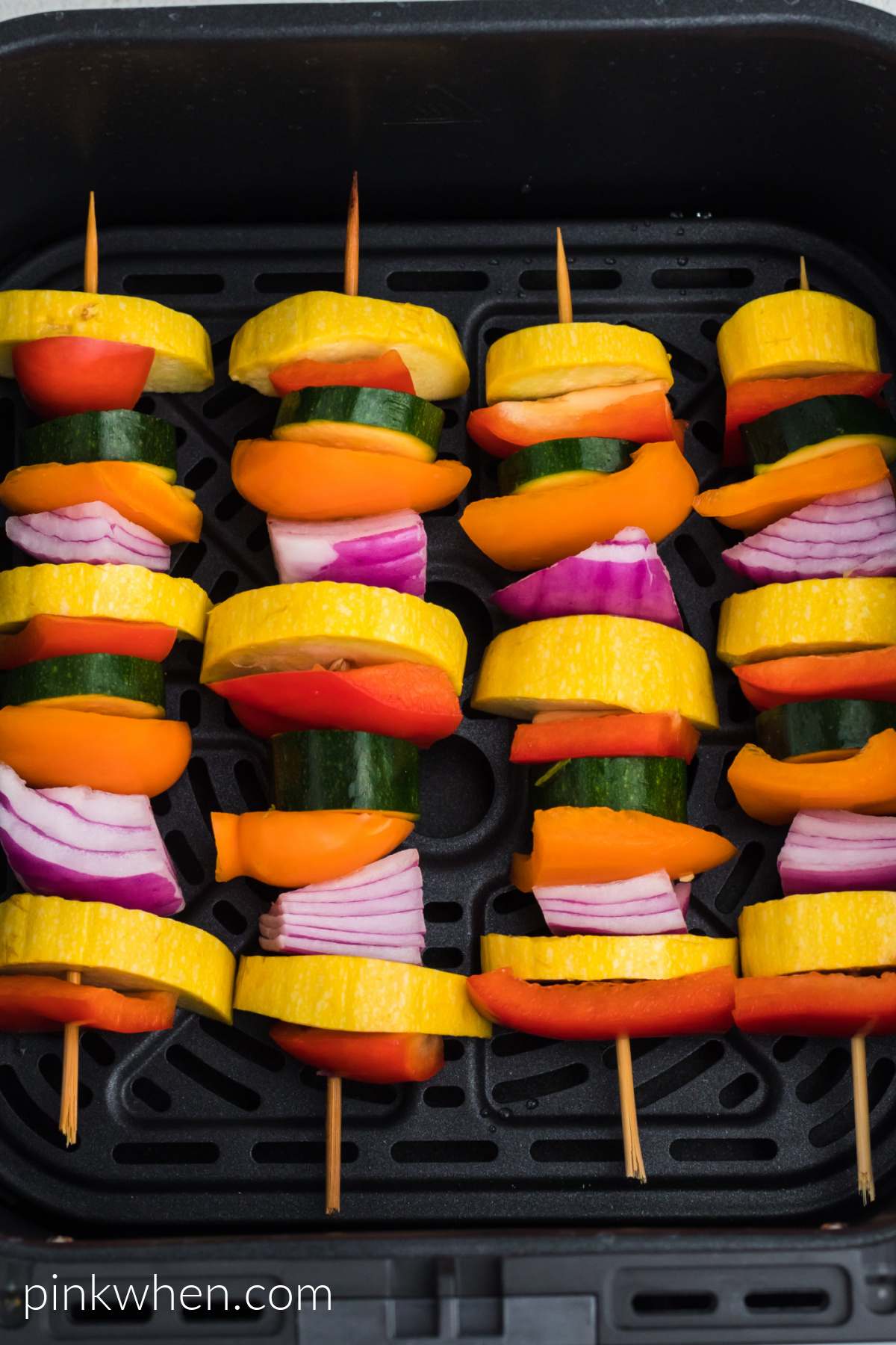 Vegetable skewers in the basket of an air fryer.