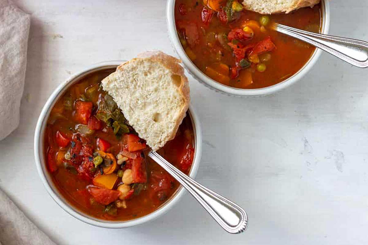 10 Vegetable Soup with bread on top of the white bowl.