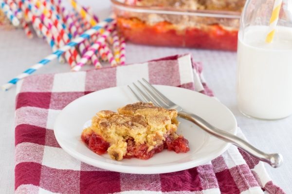 Slice of cherry cake on a white plate.