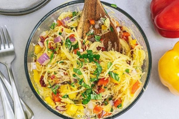 A Zesty Spaghetti Squash Salad with wooden spoon and fork. 