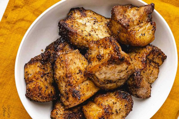 Air fryer pork belly pieces on a white plate.