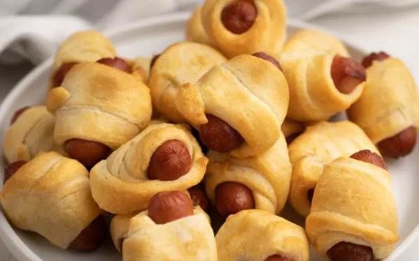 Pigs in a blanket on a white plate.