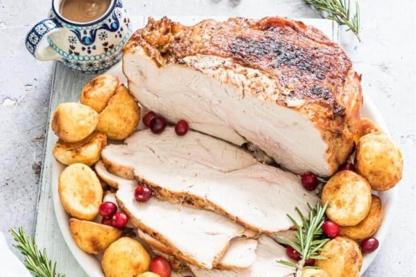 Air Fryer Turkey Breast served with potatoes, cranberries, and rosemary. 