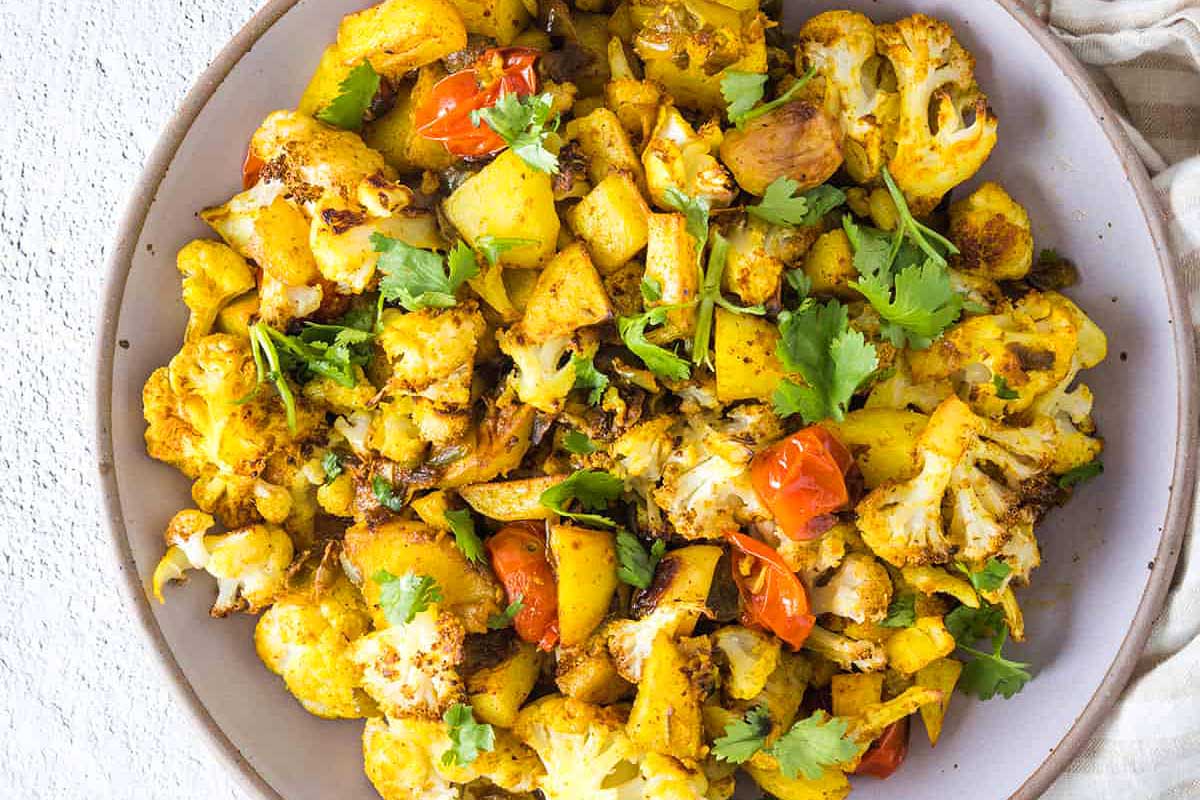 Cauliflower curry in a bowl with tomatoes and coriander.