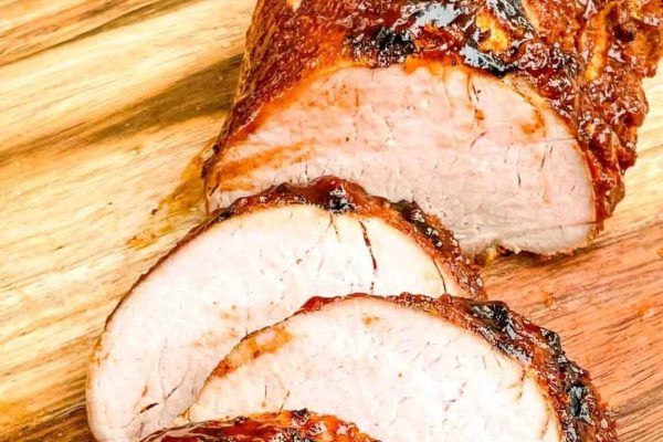 Glazed BBQ Pork Tenderloin slices on a wooden board.