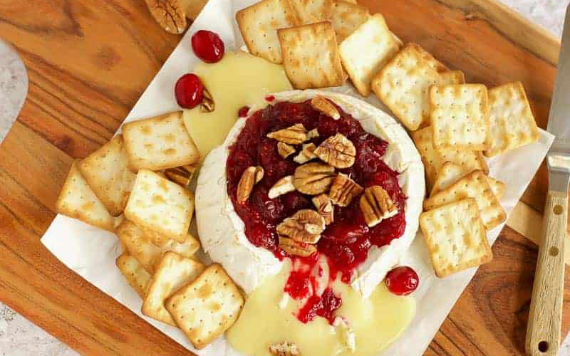 Brie with sauce on a wooden board.