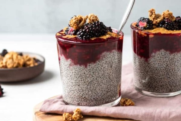 Two glasses of chia pudding with blackberries and granola.