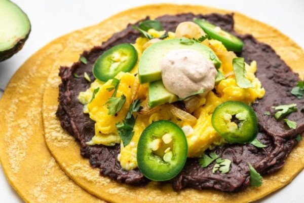 A breakfast taco with eggs, avocado and jalapenos.
