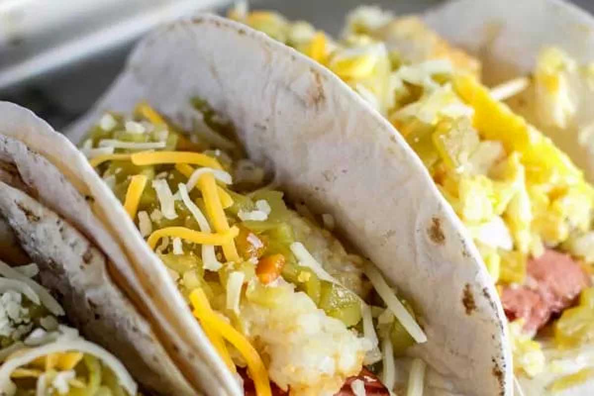 Hot dog burritos in flour tortillas with cheese on top.