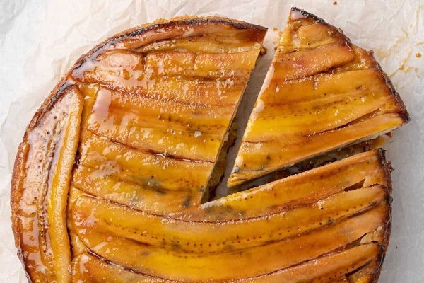 Whole Caramelized Banana Upside down cake with one slice. 