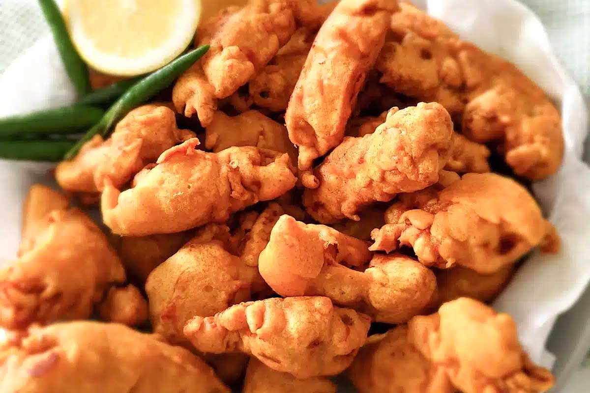 Chicken pakora in a white bowl served with lemon.
