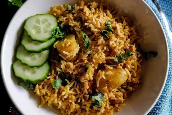 Chicken biryani with rice and cucumber slices on a bowl.