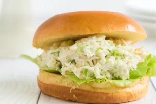 A chicken salad sandwich on a bun with lettuce.