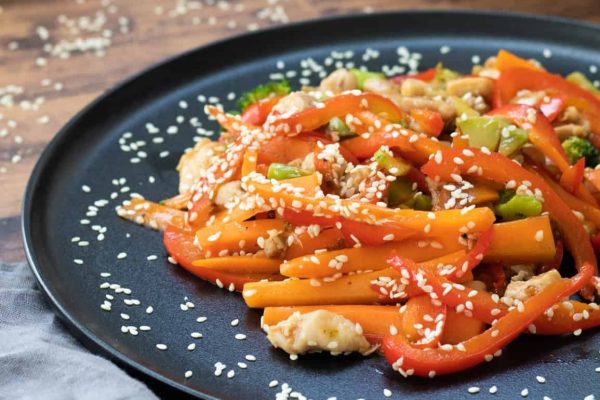 Chicken Teriyaki Stir Fry sprinkled with lots of sesame seeds in a black plate.