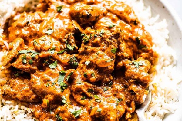 Chicken masala on rice with red sauce. 