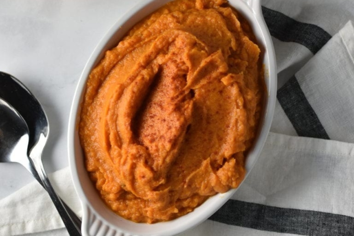 A bowl of sweet potato mashed potatoes with a spoon, perfect for sweet potato recipes.