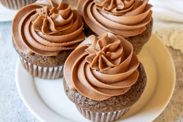 Three chocolate cupcakes on a white plate.