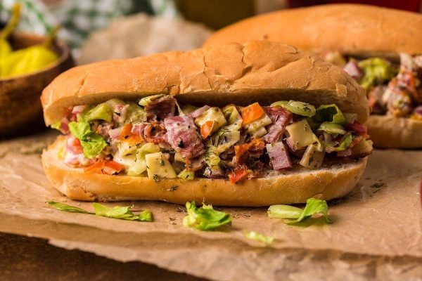 A sandwich with meat and vegetables on top of a piece of paper.