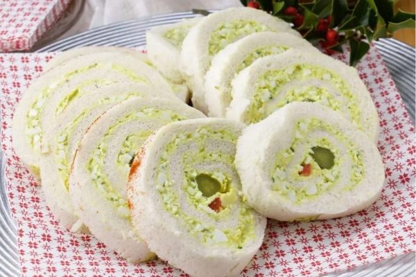 A roll of green and white bread with holly leaves on a plate.
